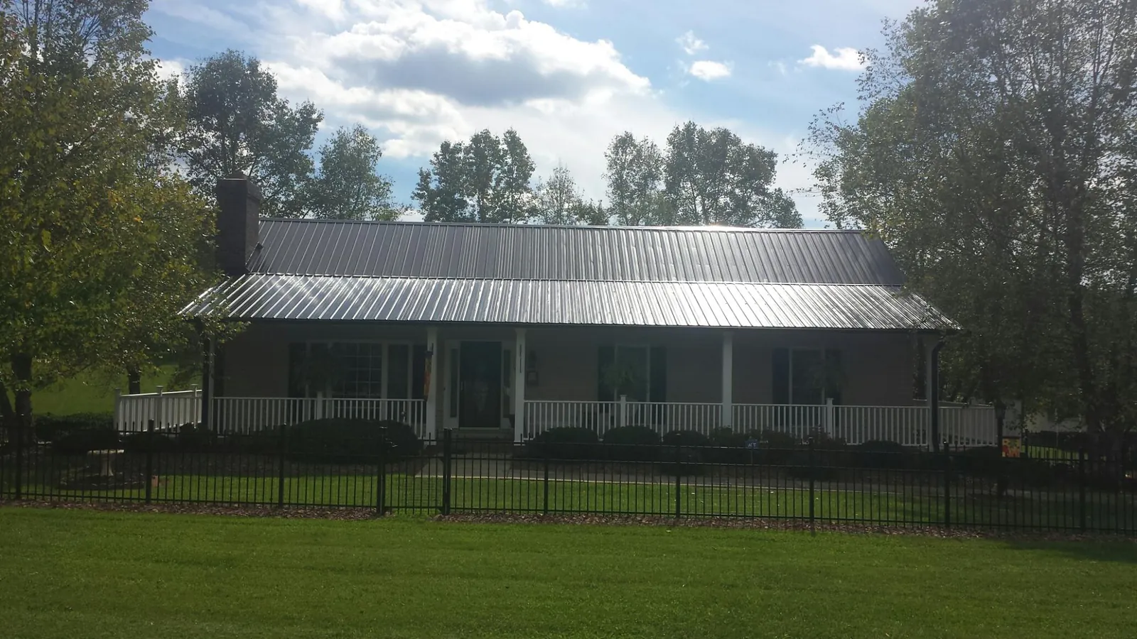 Gray metal roof on a brick ranch with a full width front porch — Gutter Guard Installation work by our crew in Miami